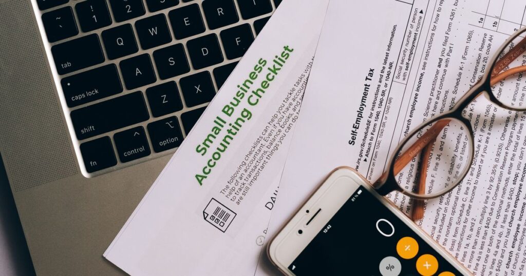 Bureau de micro-entrepreneur : ordinateur portable, checklist comptable, smartphone et documents fiscaux