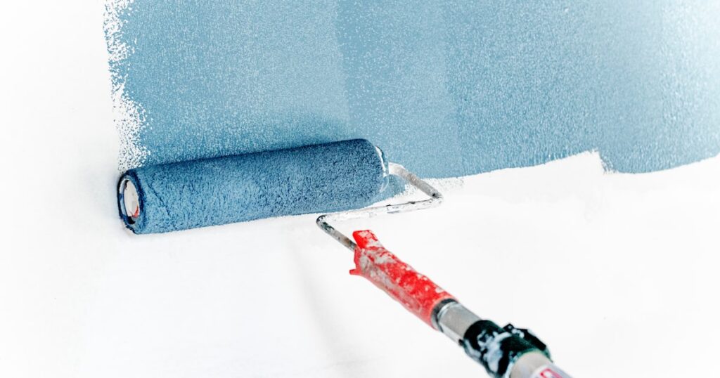Peintre en bâtiment appliquant de la peinture blanche sur un mur intérieur avec un rouleau