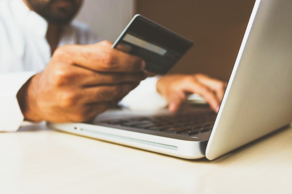 Auto-entrepreneur utilisant une carte bancaire et un ordinateur portable pour gérer son compte dédié à l’activité