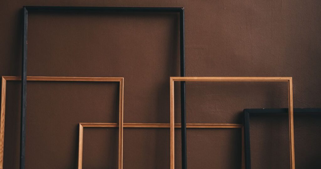 Cadres vides en bois et en métal posés contre un mur d’atelier