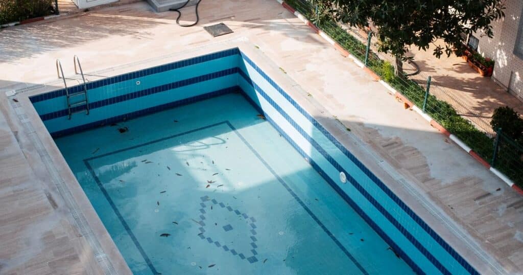 Piscine extérieure carrelée vue de haut, avec échelle et bassin à entretenir, illustrant le métier de pisciniste