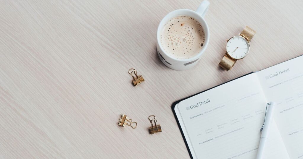 Bureau minimaliste avec agenda ouvert, tasse de café et montre, illustrant les échéances de déclaration Urssaf