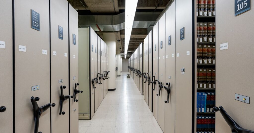 Allée d’archives avec rayonnages mobiles remplis de dossiers et de registres