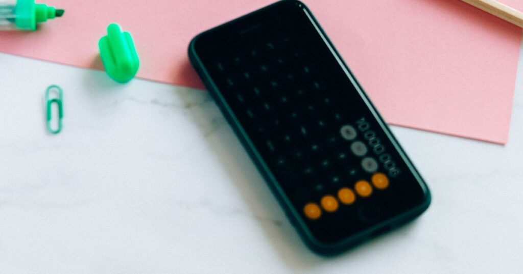 Smartphone affichant une calculatrice posé sur un bureau, pour calculer un échéancier de cotisations Urssaf